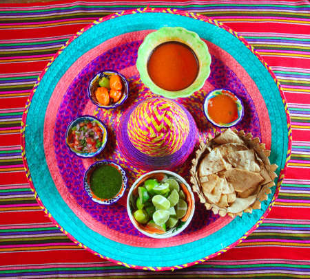 assorted Mexican sauces spices chili pico gallo on Mexican colorful hatの写真素材