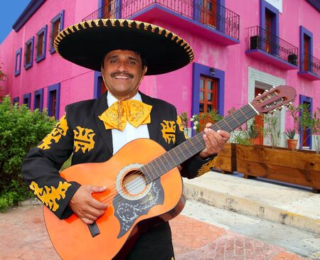 Charro Mariachi singer playing guitar in Mexico houses backgroundの写真素材