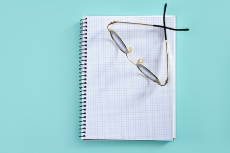 doctor or teacher glasses on blank spiral notebook copyspace over greenの写真素材