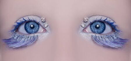 Blue eye macro closeup with a winter inspired silver makeup some jewels and feather eyelashesの写真素材