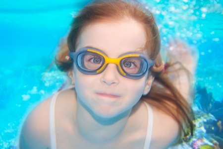 children girl swimming underwater with goggles and funny gestureの写真素材