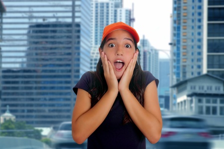 Beautiful Latin teen hispanic girl with cap and surprise gesture in urban city streetの写真素材
