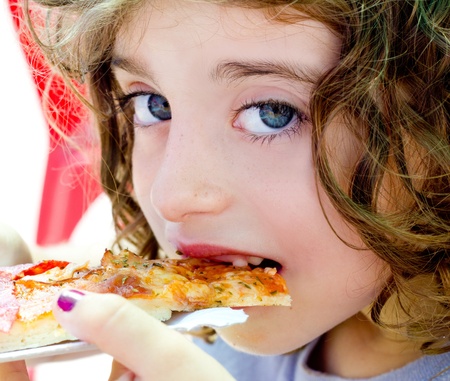 blue eyes child girl eating pizza slice hungryの写真素材