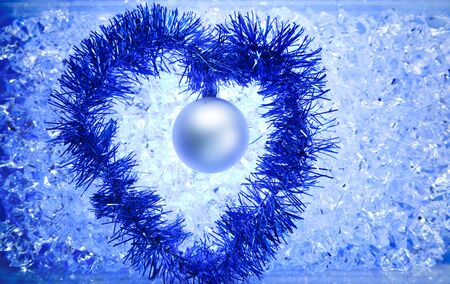 christmas silver bauble tinsel heart shape on blue winter iceの写真素材