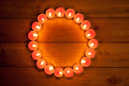 candles glowing in circle shape on golden wood backgroundの写真素材