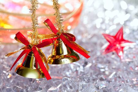 christmas golden bells with red ribbon on winter ice and starsの写真素材