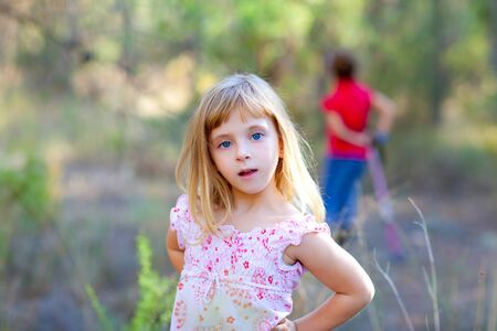 blond kid girl in forest park posing to cameraの写真素材