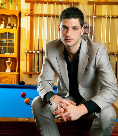 handsome man with suit sitting posing in billiard pool in club