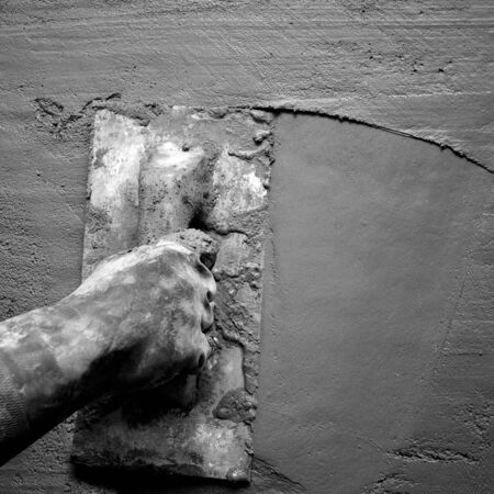 dirty trowel with glove hand plastering cement mortar in the wallの写真素材