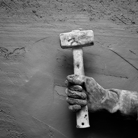 hammer man hand with gloves in grunge cement mortar backgroundの写真素材