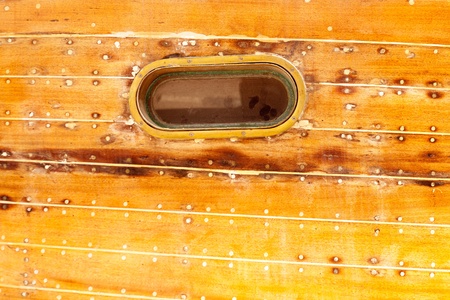 boat oval aged brass porthole in wooden hull with caulking putty and screwの写真素材