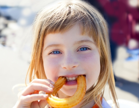 Blue eyes little girl eating churros fried crullers smilingの写真素材