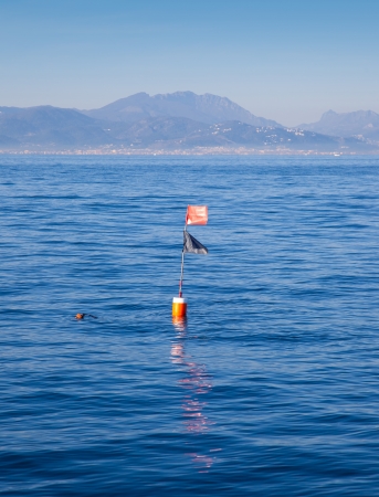 Longliner and trammel net buoy with flag pole in blue seaの写真素材