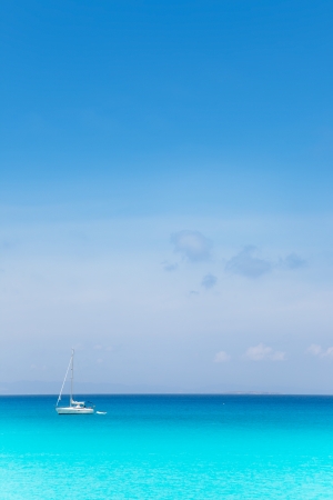 Balearic mediterranean turquoise sea with sailboat under blue skyの写真素材