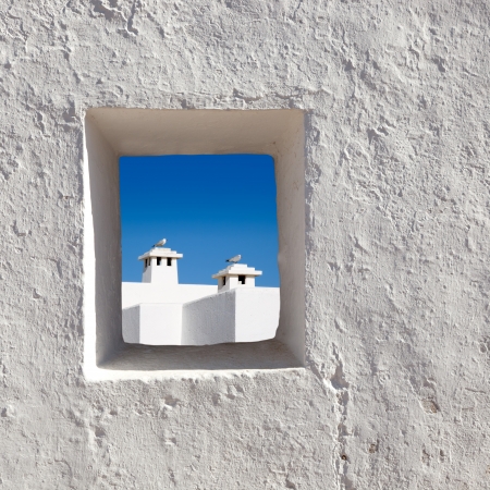 Balearic islands white chimney with seagull view through whitewashed house windowの写真素材
