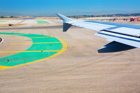 Airplane wing leaving the airport with airstrip road signsの写真素材