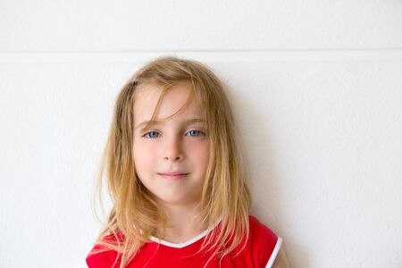 Blond beautiful kid girl smiling on a white wall portraitの写真素材