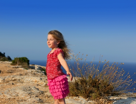 blue day with kid girl open hands to the wind and Mediterranean seaの写真素材