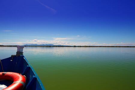 Blue boat sailing in Albufera lake of Valencia in a sunny blue sky dayの写真素材