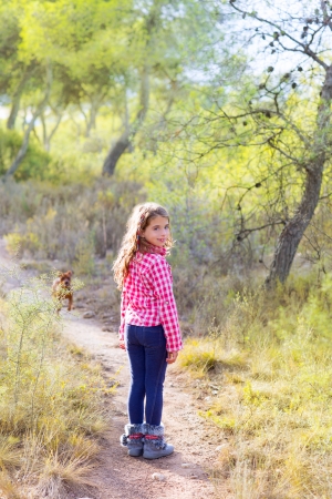 children girl walking in the pine forest with doggy aroundの写真素材