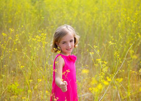 child kid girl in spring yellow flowers field and pink dress in Mediterranean forestの写真素材