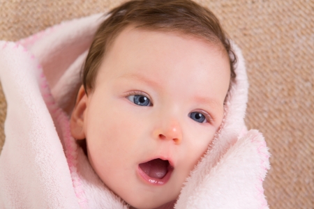 Baby little girl face portrait open mouth on pink blanketの写真素材