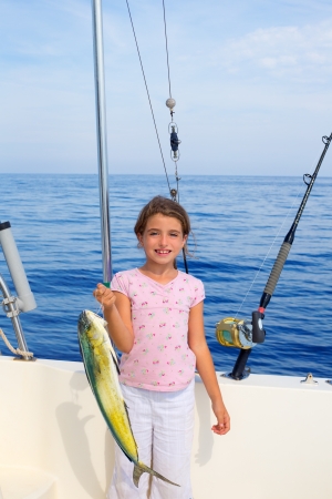 child girl fishing in boat with mahi mahi dorado fish catch with rod and trolling reelsの写真素材