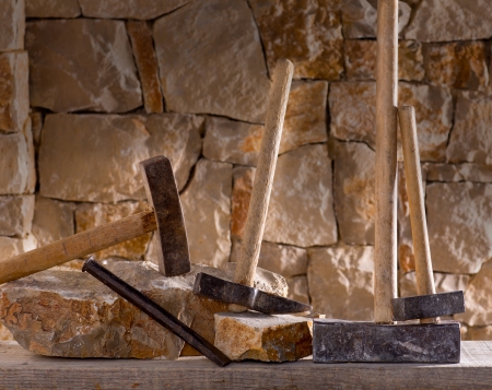 Hammer mason tools of stonecutter masonry work in a contruction stone wall