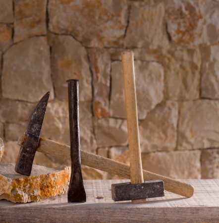 Hammer mason tools of stonecutter masonry work in a contruction stone wallの写真素材