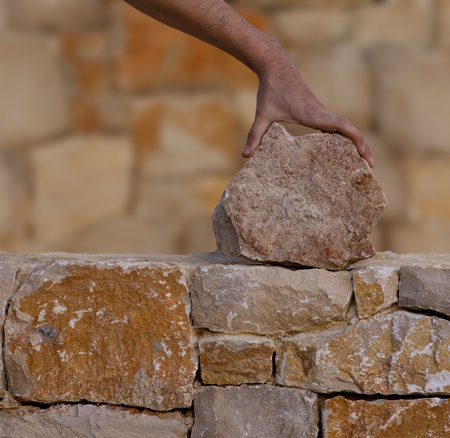 Mason hands working on masonry stone wall stonewallの写真素材