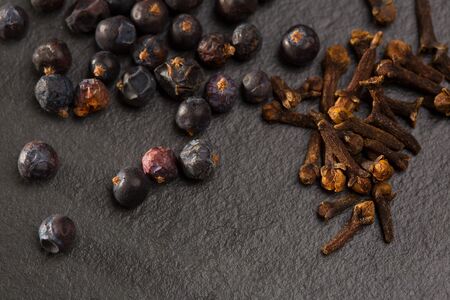 cloves and juniper berries spices on black slate stone backgroundの写真素材