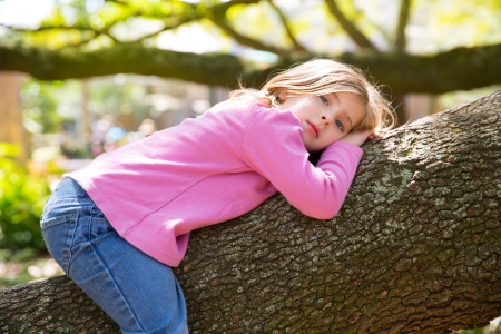 Beautiful children kid girl resting lying on a tree branchの写真素材