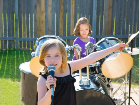 Blond kid singer girl singing playing live band in backyard concert with friendsの写真素材