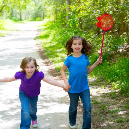 Friends and sister girls running in the forest track smiling happy with butterfly netの写真素材