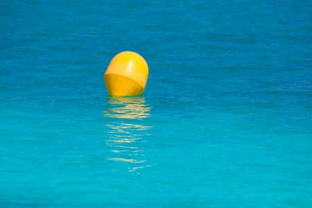 Yellow buoy floating in balearic turquoise Mediterranean sea