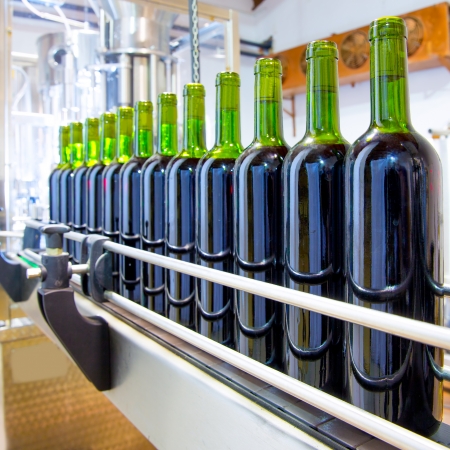 red wine in glass bottling machine at wineryの写真素材