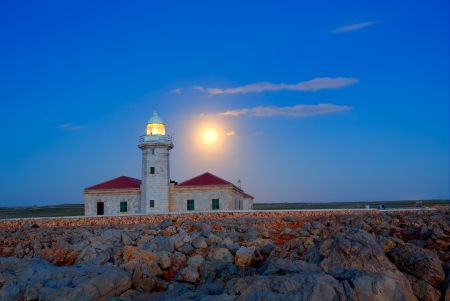 Ciutadella Menorca Punta Nati lighthouse with moon shining in skyの写真素材