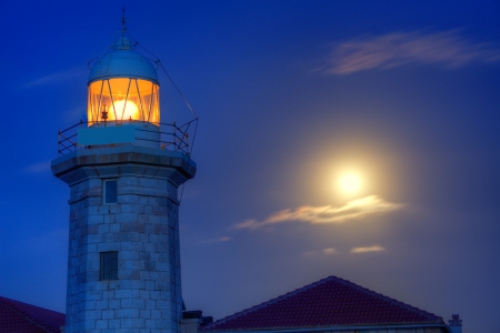 Ciutadella Menorca Punta Nati lighthouse with moon shining in skyの写真素材