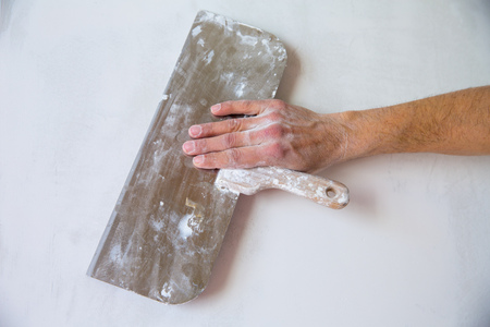 Plastering man hand with plaste and plaster spatula trowel in wallの写真素材