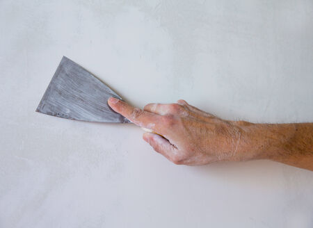 Plastering man hand with plaste and plaster spatula trowel in wallの写真素材