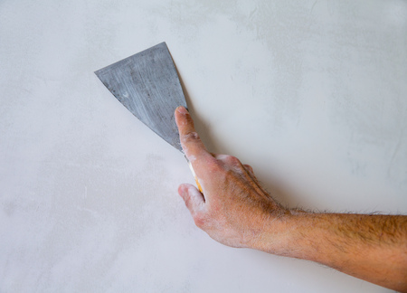 Plastering man hand with plaste and plaster spatula trowel in wallの写真素材