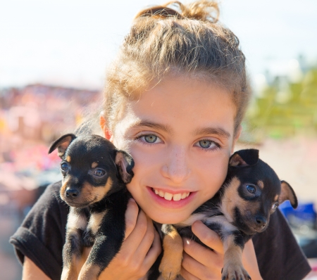 kid girl playing with puppy dogs smiling with blue eyesの写真素材