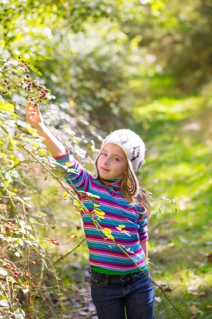 kid winter girl picking mulberry berries in the forest with wool capの写真素材
