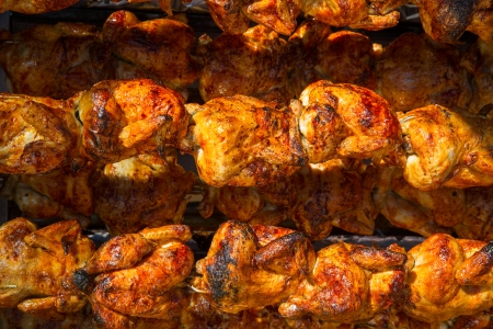 Roasted chicken in a row turning at industrial roasterの写真素材