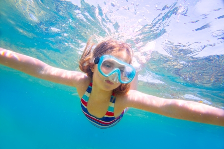 snorkeling blond kid girl underwater with goggles and swimsuit in Mediterranean seaの写真素材