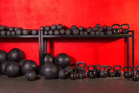 Kettlebell dumbbell and weighted slam balls weight training equipment at gym red wallsの写真素材