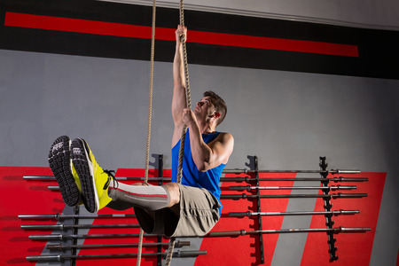 Rope Climb exercise man workout at gym climbing