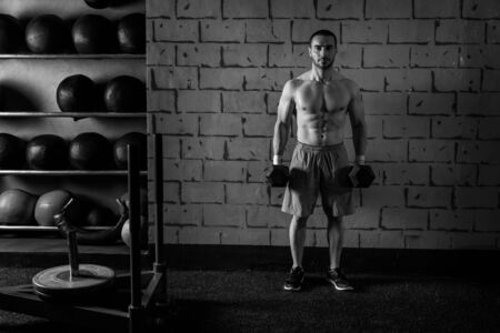 gym man holding hex dumbbells with muscle torsoの写真素材