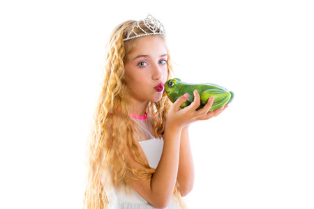 blond princess girl kissing a frog green toad like a story tale on whiteの写真素材