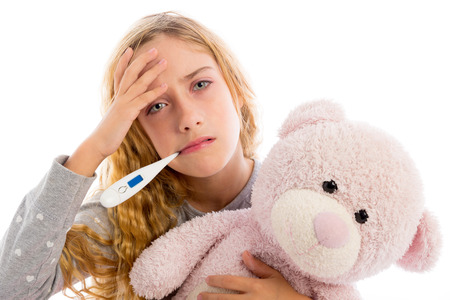 blond girl with thermometer and flu cold in pyjama  grumpy face with teddy bearの写真素材